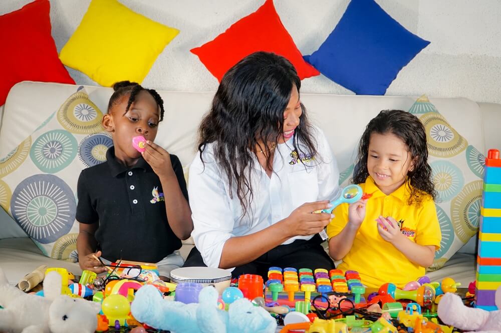 eacher guiding two preschoolers during a hands-on toy exploration session at Better Life Club Haiti